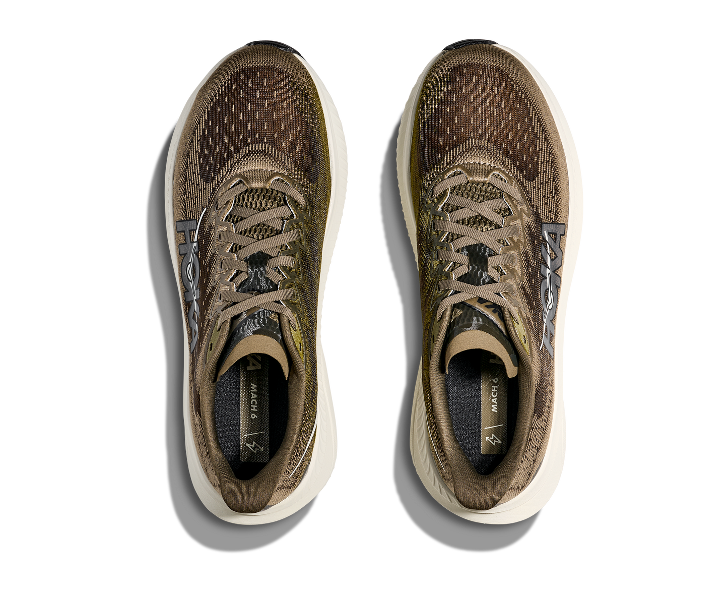 Hoka M Mach 6, superskum med syretillförsel i gummit för att minimera vikt och skapa en så responsiv sko som möjligt. Mach 6 är en snabb löparsko för intervallpass, tävling och löpbandet. Färgen här går i gröna och bruna nyanser med beige sula. Köpt hos oss, din Hoka specialist i Sverige.