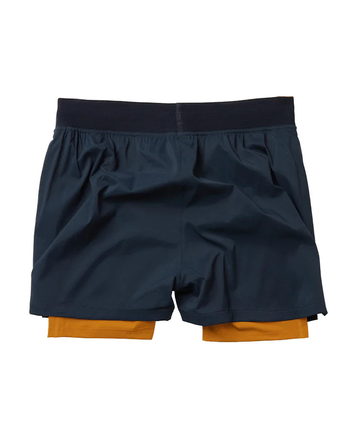 Marinblå 2-1 shorts med ett ytterlager av lätt funktionsmaterial. Under finns ett par gula kompressionstights med sidfickor på båda benen. Vit logotyp på framsidan, vänster ben. Midjebandet säkras med invändig snörning.