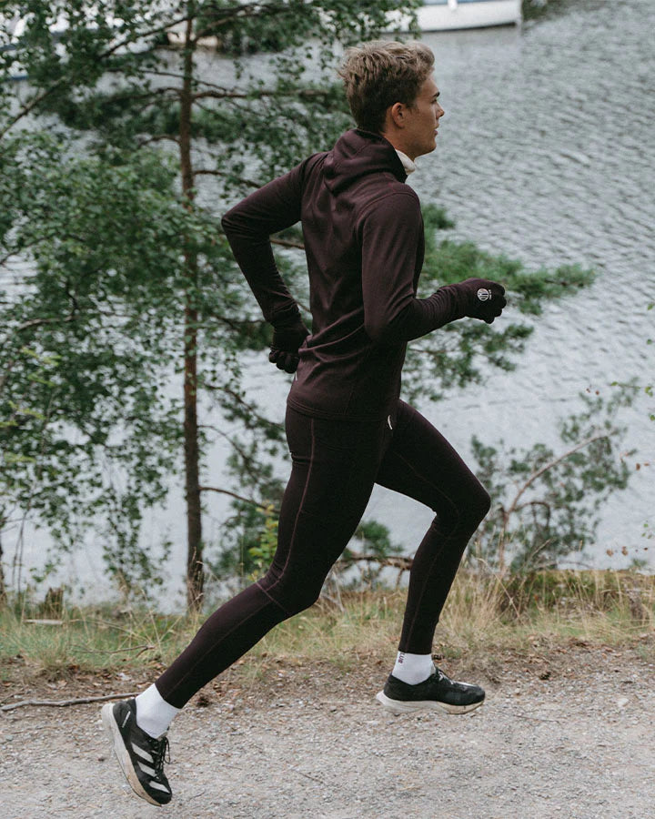 YMR Åsunden Men's Hoodie. Hoodie i rödbrun nyans med beige kontrastfärg på insidan av luvan och på loggan på bröstet. Huva med hög krage och tumöppningar i ärmsluten. Tight, sportig passform.