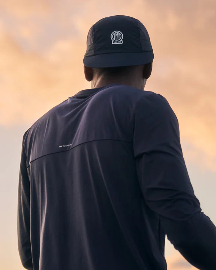 YMR Bäckaryd Performance Cap. Marinblå keps med meshpaneler på sidorna. Logotyp YMR Track Club framtill och text bak "TRACK, TRAIL & ROAD" i vita reflexdetaljer.