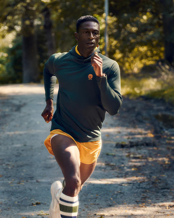 YMR Åsunden Men's Hoodie. Grön hoodie med gul kontrastfärg på insidan av luvan och loggan på bröstet. Huva med hög krage och tumöppningar i ärmsluten. Tight, sportig passform.
