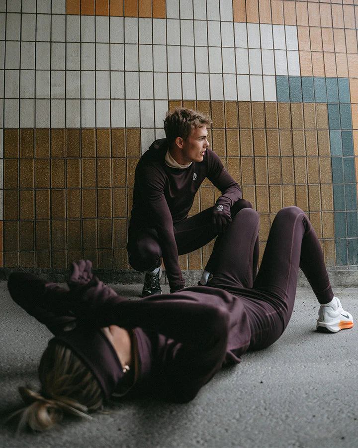 YMR Åsunden Men's Hoodie. Hoodie i rödbrun nyans med beige kontrastfärg på insidan av luvan och på loggan på bröstet. Huva med hög krage och tumöppningar i ärmsluten. Tight, sportig passform.