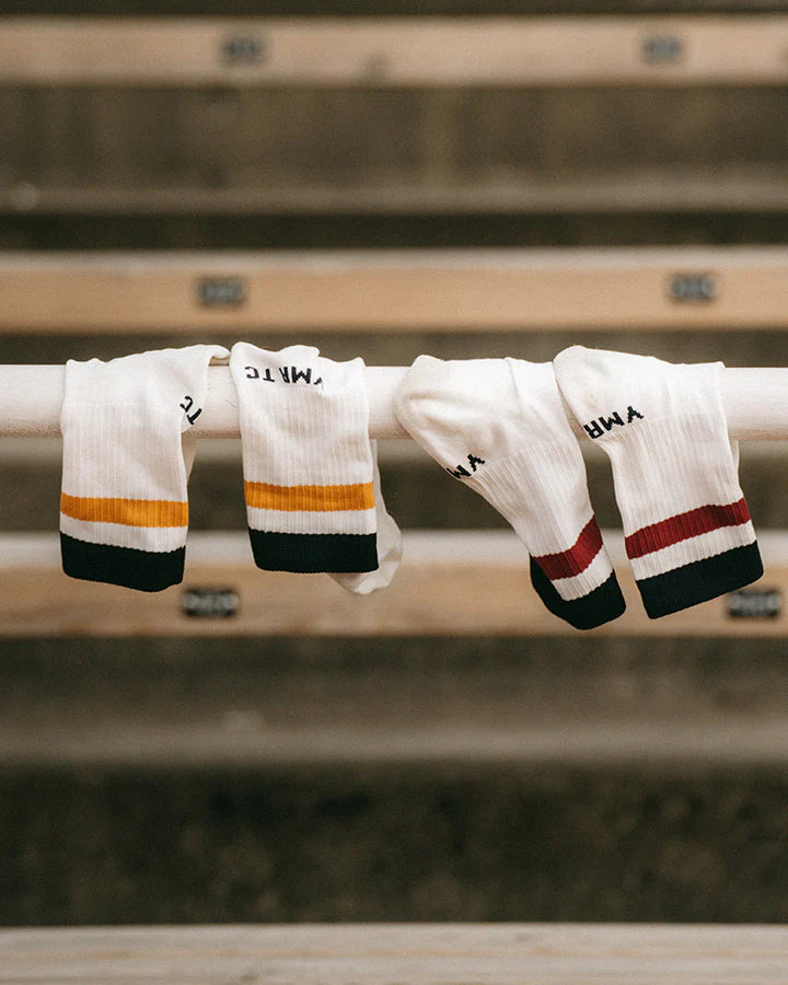 YMR Åsunden Mid Crew Socks. Vita strumpor med en röd och en blå rand upptill. Text "YMR TC" ovanför hälen. Extra vaddering under foten och vid hälen för ökad komfort och slitstyrka vid löpning eller annan fysisk aktivitet.