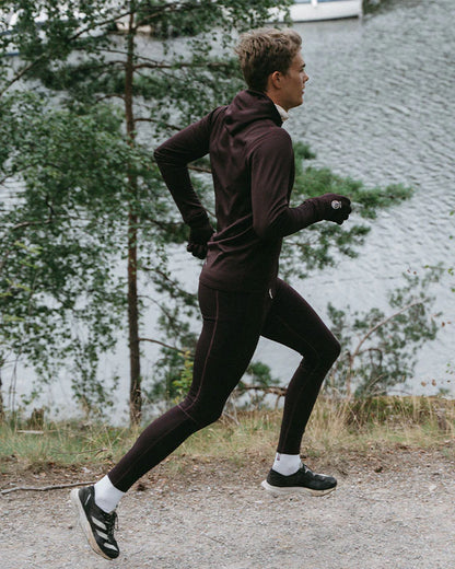 YMR Åsunden Men's Hoodie. Hoodie i rödbrun nyans med beige kontrastfärg på insidan av luvan och på loggan på bröstet. Huva med hög krage och tumöppningar i ärmsluten. Tight, sportig passform. 