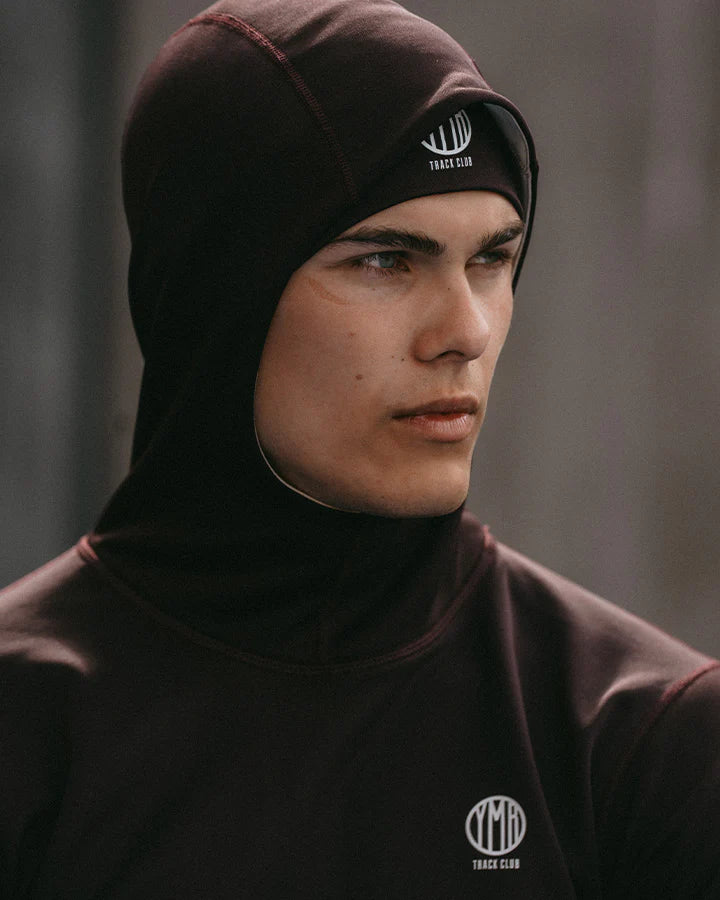 YMR Åsunden Men's Hoodie. Hoodie i rödbrun nyans med beige kontrastfärg på insidan av luvan och på loggan på bröstet. Huva med hög krage och tumöppningar i ärmsluten. Tight, sportig passform. 