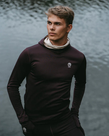 YMR Åsunden Men's Hoodie. Hoodie i rödbrun nyans med beige kontrastfärg på insidan av luvan och på loggan på bröstet. Huva med hög krage och tumöppningar i ärmsluten. Tight, sportig passform. 