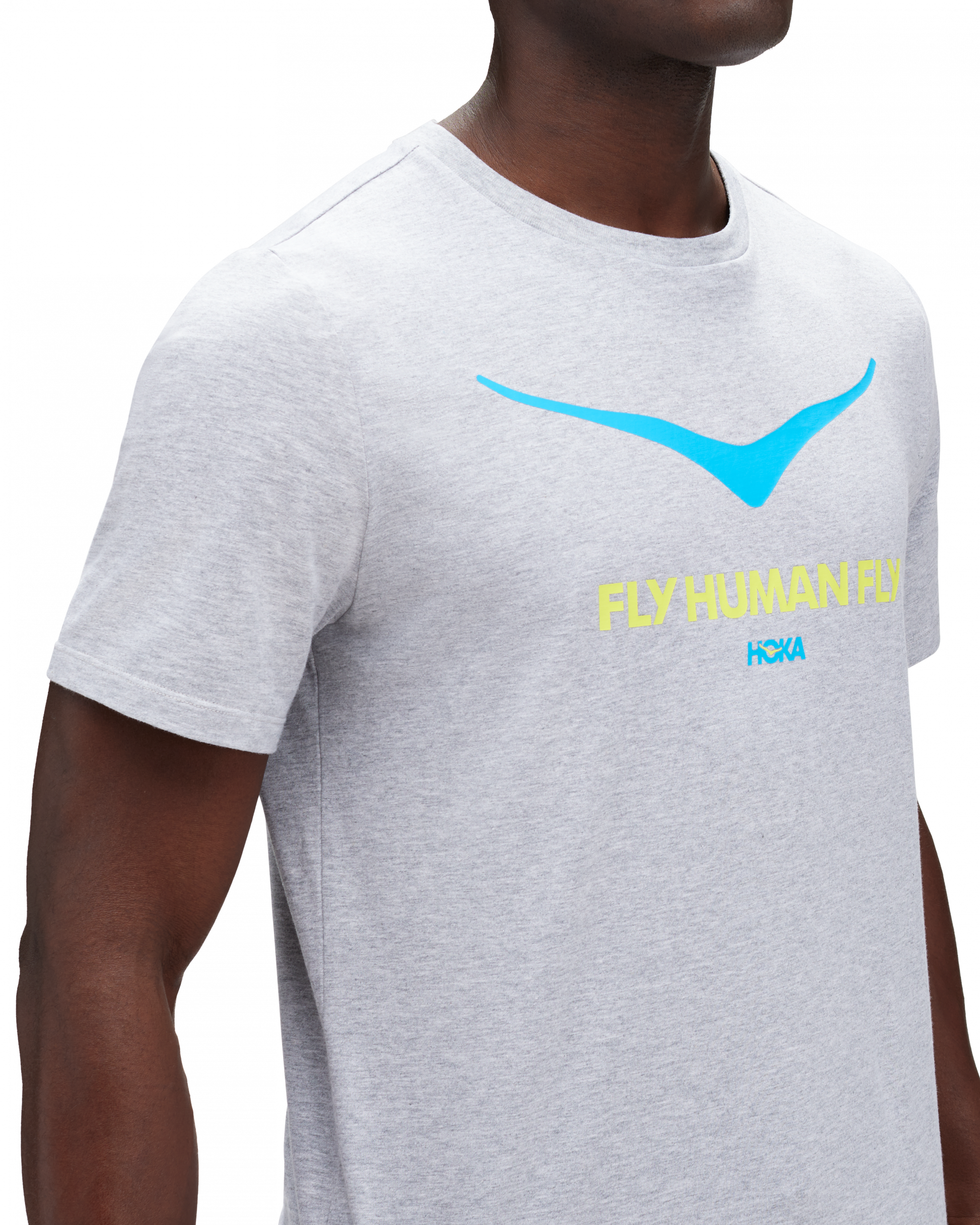 Skön grå T-Shirt med Hoka loggan i blått på bröstkorgen. Under loggan står det "FLY HUMAN FLY" i grön färg.