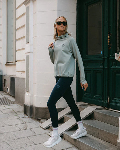 YMR Åsunden Ladies Funnel Neck Mint. Ljusgrön mångsidig och mjuk tröja med mörkblått inuti den höga kragen och på logotyp på bröstet. Dragsko i både kragen och i midjan för justerbar passform. Reflexdetalj på nedre delen av ryggen. 