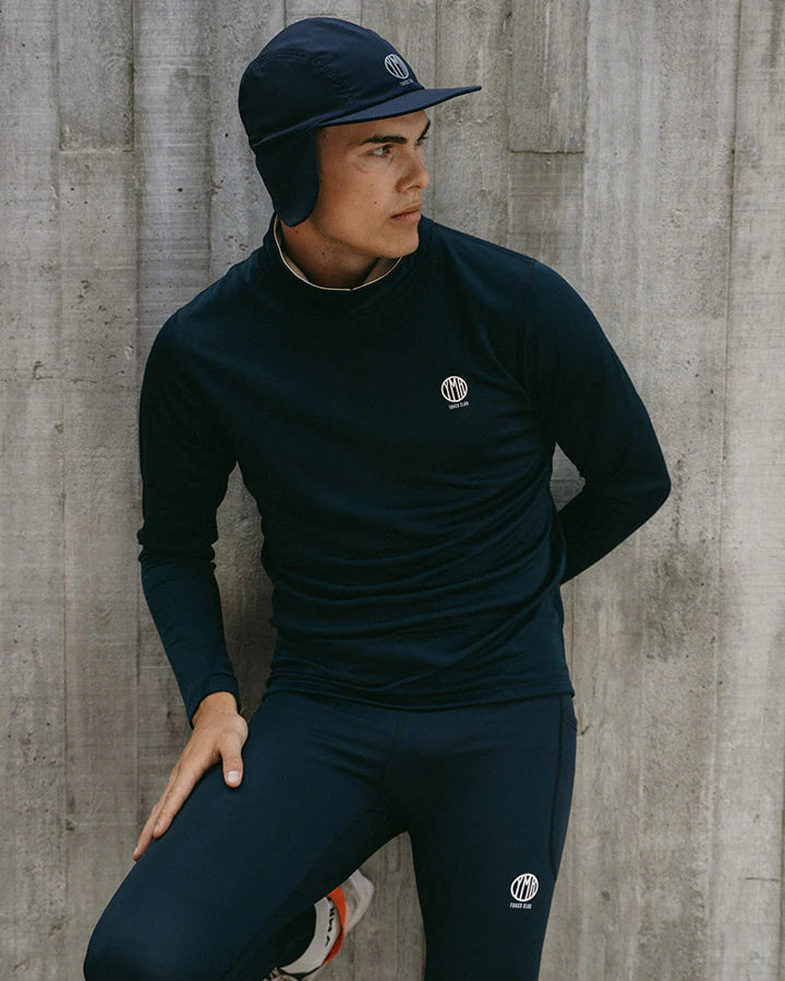 YMR Åsunden Men's Funnel Neck Navy. Mångsidig och mjuk tröja i marinblått med beige inuti den höga kragen och på logotyp på bröstet. Dragsko i både kragen för justerbar passform. Reflexdetalj på nedre delen av ryggen. 