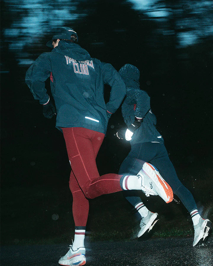 Vind- och vattenavvisande mörkblå löparjacka för herr med huva och ventilation.
Ventilation i stickad mesh under armarna, dragskojusterbar huva som kan rullas in i kragen, samt dragkedjeförsedda sidfickor för förvaring. Jackan pryds av YMR:s logotyp i off-white framtill och ett reflexprint i svanken för ökad synlighet i mörker. Logga i Offwhite och vinrött på ryggen. Mudd i ärmslut i vitt och vinrött. 