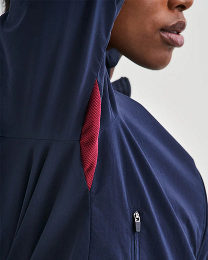 Vind- och vattenavvisande mörkblå löparjacka för dam med huva och ventilation.
Ventilation i stickad mesh under armarna, dragskojusterbar huva som kan rullas in i kragen, samt dragkedjeförsedda sidfickor för förvaring. Jackan pryds av YMR:s logotyp i off-white framtill och ett reflexprint i svanken för ökad synlighet i mörker. Logga i Offwhite och vinrött på ryggen. Mudd i ärmslut i vitt och vinrött. Dragsko i midjan.